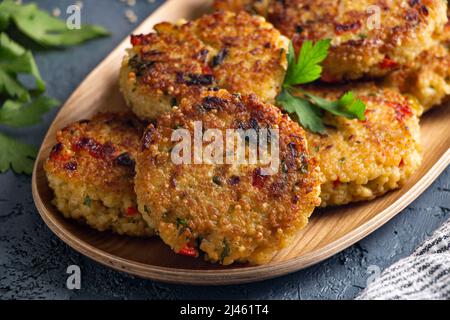 Millet végétarien sans gluten et hamburgers de légumes dans une assiette en bois Banque D'Images