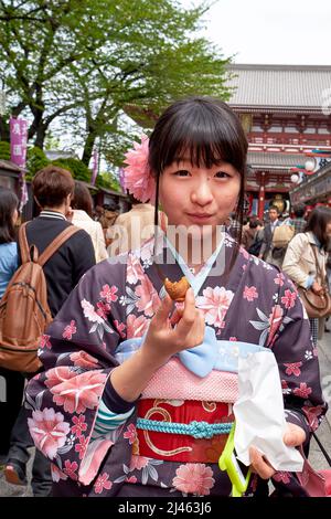 Japon. Tokyo. Une fille goûtant des bonbons dans les rues d'Asakusa Banque D'Images