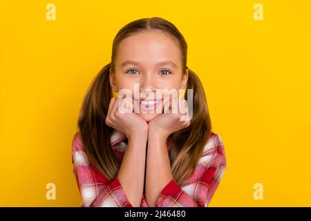 Photo de mignon adorable écolière porter chemise à carreaux bras joues sourire isolé couleur jaune fond Banque D'Images