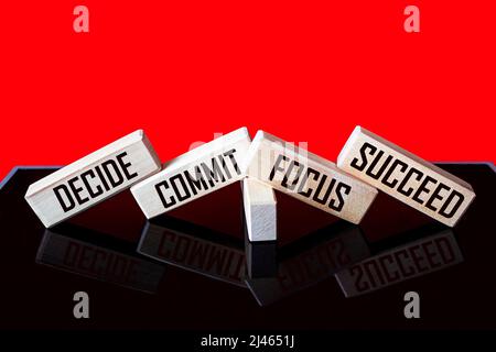 Citations motivationnelles et inspirantes - décider, s'engager, se concentrer, réussir sur des blocs de bois et arrière-plan rouge noir Banque D'Images