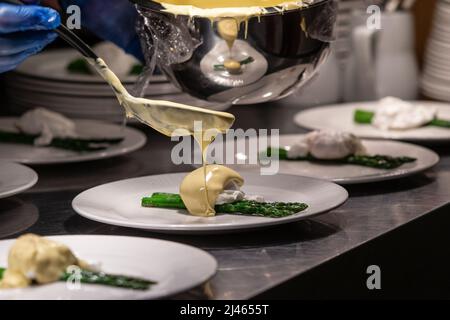 Sauce hollandaise versée sur l'œuf poché et les asperges. Banque D'Images