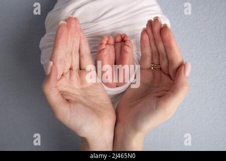 Les paumes du père, la mère tient le pied du nouveau-né dans une couverture blanche. Pieds du nouveau-né. Banque D'Images