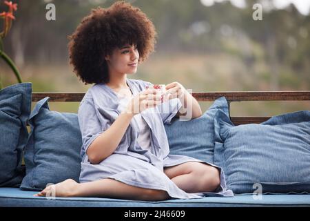 Belle vue, il a mis au feu pour quelque chose de nouveau. Photo d'une jeune femme attrayante se relaxant avec une tasse de café à l'extérieur sur le patio. Banque D'Images