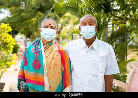 Couples âgés avec masque médical pendant la promenade matinale au parc - concept de la protection contre le coronavirus Covid-19, des soins de santé et de la sécurité. Banque D'Images