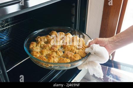 Femme prenant un plateau de baklava du four, des tranches de dessert turc maison avec des noix. Fête du Ramadan (Ramazan Bayrami) ou du sucre (Seker) en Turquie. Banque D'Images