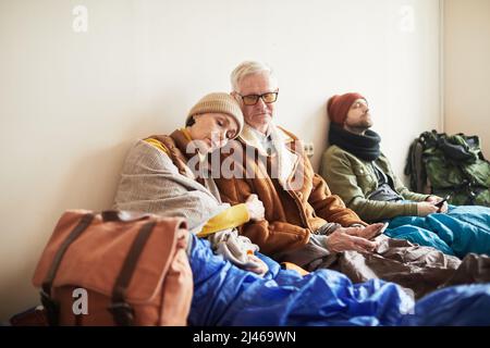 Portrait d'un couple âgé de race blanche se cachant dans un refuge pour réfugiés avec une femme dormant sur l'épaule d'un mari Banque D'Images