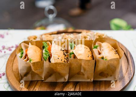 Un groupe de HAMBURGERS faits maison est enveloppé de papier artisanal et disposé sur le plat, prêt à servir et à manger. Banque D'Images