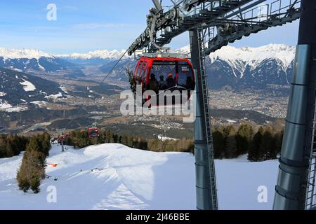 Le téléphérique de Patscherkofelbahn s'approche de la gare de Bergstation; Innsbruck s'étend le long de la vallée de l'Inn en contrebas; chaîne de montagnes de Nordkette derrière Banque D'Images