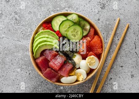 Boîte en papier ou paquet avec salade de thon à l'avocat à emporter ou livraison de nourriture avec baguettes sur fond gris. Vue du dessus. Une alimentation saine Banque D'Images