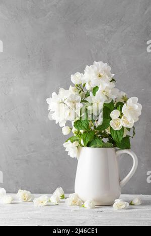 Arrière-plan de mariage. Fleurs de jasmin blanches dans un vase sur une table en bois blanche. Encore la vie. Orientation verticale Banque D'Images