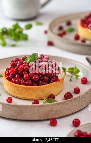 Tarte aux baies. Gâteaux de pâtisserie française aux baies de cowberry, sucre en poudre et menthe. Dessert savoureux. Orientation verticale Banque D'Images