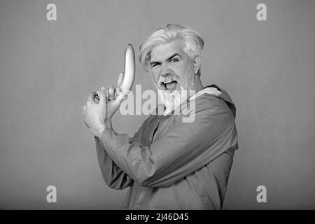 Drôle homme barbu tient un pistolet dans sa main et pose pour la caméra Banque D'Images