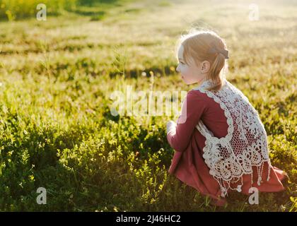 jeune fille assise dans un champ vert Banque D'Images