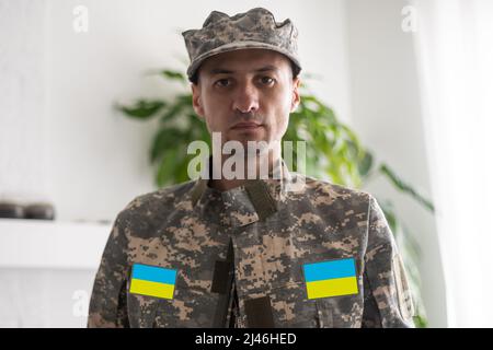 L'homme ukrainien guerrier vêtu d'un uniforme militaire de pixel le drapeau jaune-bleu de l'Ukraine Banque D'Images