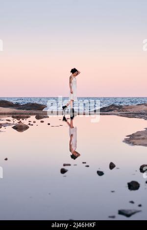 Femme dans une robe blanche reflétée dans l'eau Banque D'Images