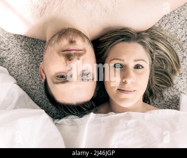 Un jeune couple heureux allongé les uns à côté des autres Banque D'Images