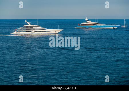 Les deux immenses yachts sont amarrés en mer par temps ensoleillé, la main courante chromée, le soleil se réfléchit sur le panneau brillant du bateau à moteur Banque D'Images