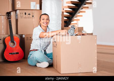 Je passe à des choses plus grandes et plus performantes. Prise de vue d'une jeune femme scellant des boîtes en carton avec un ruban à la maison. Banque D'Images