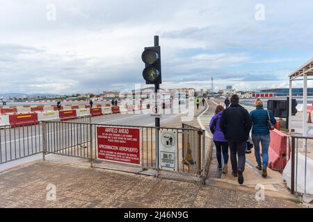 GIBRALTAR, GRANDE-BRETAGNE - AVRIL 7 2022 : les touristes franchissent la piste de l'aéroport de Gibraltar tandis que la lumière piétonne est verte. Banque D'Images