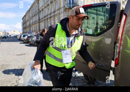 Przemysl, Pologne. 12th avril 2022. Le volontaire canadien Michael Garnet, joueur professionnel de hockey du Canada qui a également vécu en Russie pendant 8 ans et parle couramment russe, est venu en Pologne, a loué une fourgonnette de 8 passagers, et maintenant sert 18 heures par jour conduire les plus vulnérables des réfugiés entre les sites humanitaires et les centres de transport jusqu'à ce qu'ils soient en sécurité sur leur chemin vers de nouvelles maisons. Il se dit que 80% des Ukrainiens qu'il a rencontrés parlent russe ; beaucoup d'entre eux parlent exclusivement russe et beaucoup ont des histoires déchirantes d'évasions étroites et de terreur dans leurs villes d'origine. Ici, il porte les bagages d'une femme, Banque D'Images