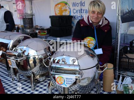 Przemysl, Pologne. 12th avril 2022. Les réfugiés ukrainiens reflétés dans le conteneur de service en métal reçoivent un délicieux ragoût de bœuf chaud pour le déjeuner à la tente de World Central Kitchen à Tesco. Les réfugiés passent par Tesco, l'un des principaux centres humanitaires pour les réfugiés ukrainiens près de la frontière entre l'Ukraine et la Pologne. Ils sont récemment arrivés en Pologne après avoir fui la terreur de Poutine en Ukraine. (Image de crédit : © Amy Katz/ZUMA Press Wire) Banque D'Images