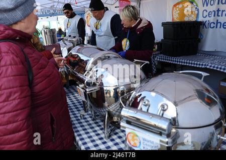 Przemysl, Pologne. 12th avril 2022. Les réfugiés ukrainiens reflétés dans le conteneur de service en métal reçoivent un délicieux ragoût de bœuf chaud pour le déjeuner à la tente de World Central Kitchen à Tesco. Les réfugiés passent par Tesco, l'un des principaux centres humanitaires pour les réfugiés ukrainiens près de la frontière entre l'Ukraine et la Pologne. Ils sont récemment arrivés en Pologne après avoir fui la terreur de Poutine en Ukraine. (Image de crédit : © Amy Katz/ZUMA Press Wire) Banque D'Images