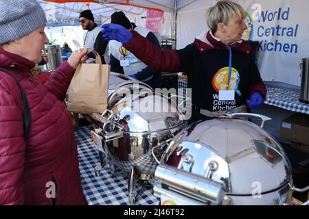 Przemysl, Pologne. 12th avril 2022. Les réfugiés ukrainiens reflétés dans le conteneur de service en métal reçoivent un délicieux ragoût de bœuf chaud pour le déjeuner à la tente de World Central Kitchen à Tesco. Les réfugiés passent par Tesco, l'un des principaux centres humanitaires pour les réfugiés ukrainiens près de la frontière entre l'Ukraine et la Pologne. Ils sont récemment arrivés en Pologne après avoir fui la terreur de Poutine en Ukraine. (Image de crédit : © Amy Katz/ZUMA Press Wire) Banque D'Images