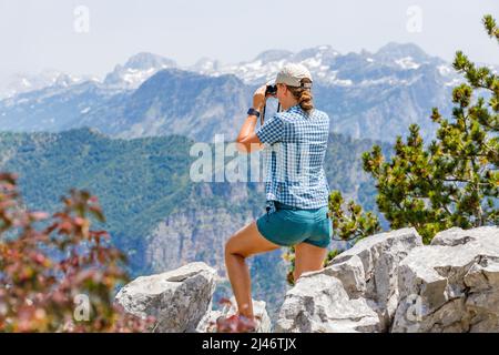 Jeune touriste regardant les oiseaux dans les montagnes. Petite fille de randonneur avec jumelles Banque D'Images