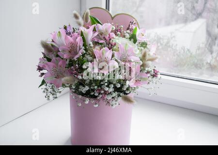 Bouquet délicat de lys roses, roses blanches et gitsophila dans une boîte cadeau de mot d'amour sur la fenêtre. Banque D'Images