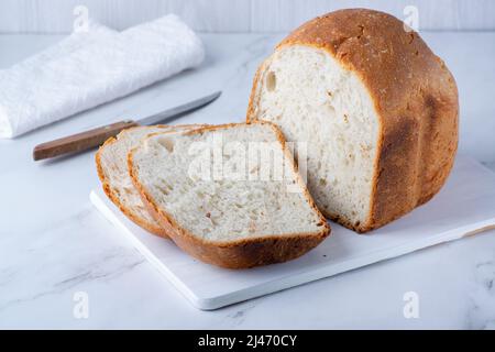 Pain fraîchement cuit sur une table blanche. Une alimentation saine. Banque D'Images