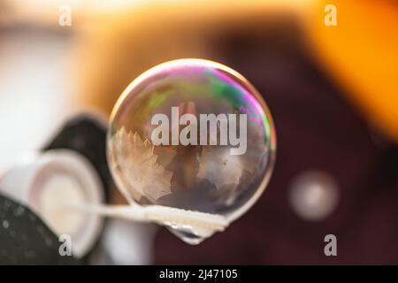 une fille tient une bulle de savon avec de beaux motifs de gel dans les rayons du soleil en hiver Banque D'Images