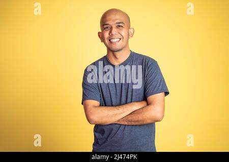 chauve homme portant t-shirt souriant avec les mains croisées Banque D'Images