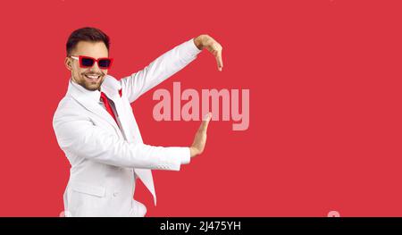 Homme souriant en costume dansant sur fond rouge Banque D'Images