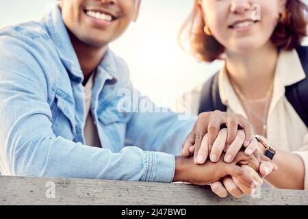 Notre moyen de voyage préféré est de voyager ensemble. Photo courte d'un jeune couple tenant les mains en se tenant debout à l'extérieur. Banque D'Images