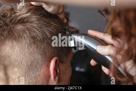 couper les cheveux à l'aide d'une tondeuse, coiffeur rasages les cheveux. Banque D'Images