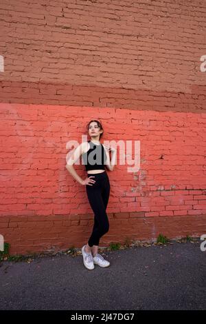 Danseuse adolescente debout près du bâtiment en briques peintes dans le centre-ville de Berkeley Banque D'Images