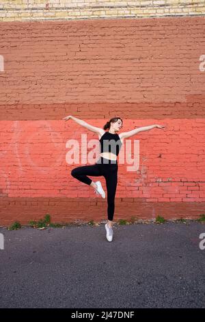 Danseuse adolescente debout près du bâtiment en briques peintes dans le centre-ville de Berkeley Banque D'Images