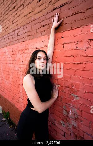 Danseuse adolescente debout près du bâtiment en briques peintes dans le centre-ville de Berkeley Banque D'Images