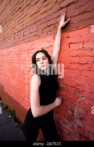 Danseuse adolescente debout près du bâtiment en briques peintes dans le centre-ville de Berkeley Banque D'Images