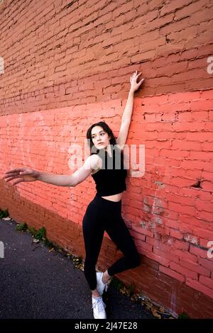 Danseuse adolescente debout près du bâtiment en briques peintes dans le centre-ville de Berkeley Banque D'Images