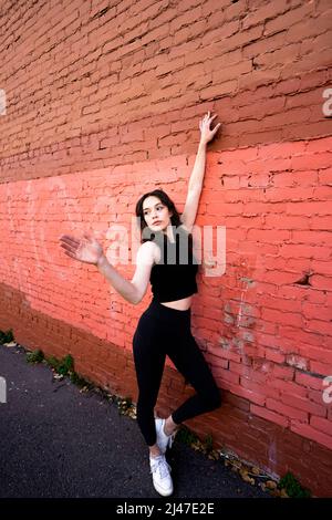 Danseuse adolescente debout près du bâtiment en briques peintes dans le centre-ville de Berkeley Banque D'Images