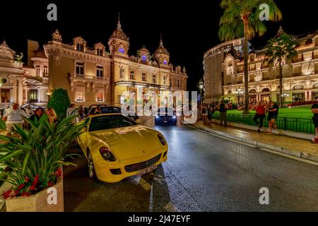 Monaco, Monte Carlo, 21 août 2019: Voiture de sport de luxe Ferrari près de l'hôtel Paris et casino de nuit, lumières de la place Casino, beaucoup de touristes Banque D'Images