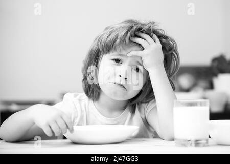 Pas faim. Enfant refusant de manger. L'enfant n'a pas d'appétit. Le petit enfant contrarié refuse de manger des céréales biologiques avec du lait. Nutrition de l'enfant. Banque D'Images