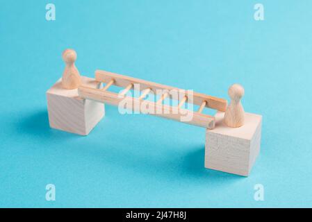 Deux personnes se connectent par une échelle, en intimidant un pont entre les hommes, la séparation et le concept de connexion, se rencontrant pour dépasser les frontières Banque D'Images