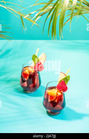 Verres avec cocktail Sangria traditionnel décoré avec des morceaux de fraise fraîche, une pincée de menthe et de paille en papier écologique. Banque D'Images