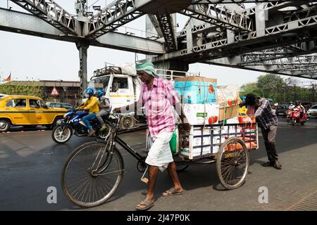 Inde, Bengale occidental, Kolkata, les hommes poussent un chariot chargé de marchandises à travers le pont Howrah Banque D'Images