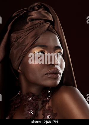 Balancer sa tête enveloppante. Photo en studio d'une jeune femme attrayante posant dans une tenue africaine traditionnelle sur un fond noir. Banque D'Images