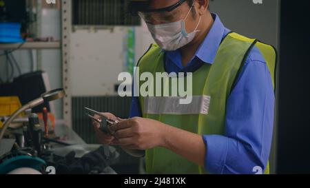 Technicien d'usine asiatique, homme travaillant à mesurer la taille de détail de l'acier avec un pied à coulisse numérique dans l'atelier Banque D'Images