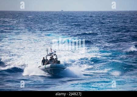 220406-N-GF955-1019 MER DES CARAÏBES - (6 AVRIL 2022) -- Les gardes-côtes affectés au “Los Ochos Locos” du détachement de police (LEDET) 408 et les marins affectés au navire de combat littoral Freedom-variant USS Billings (LCS 15) récupèrent le bateau à coque rigide (RHIB) après avoir effectué des opérations de lutte contre les narcotiques gonflables avec le Cutter de la Garde côtière Joseph Tezanos (WPC 1118), le 6 avril 2022. Billings est déployé dans la zone d’opérations de la flotte américaine 4th afin d’appuyer la mission de la Force opérationnelle interagences conjointe Sud, qui comprend des missions de lutte contre le trafic de drogues illicites dans les Caraïbes et à Pâques Banque D'Images