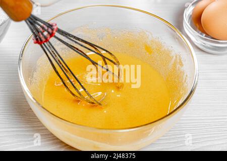 Battez les jaunes d'œufs avec du sucre, de la vanille et de la cannelle dans un bol en verre avec un fouet Banque D'Images
